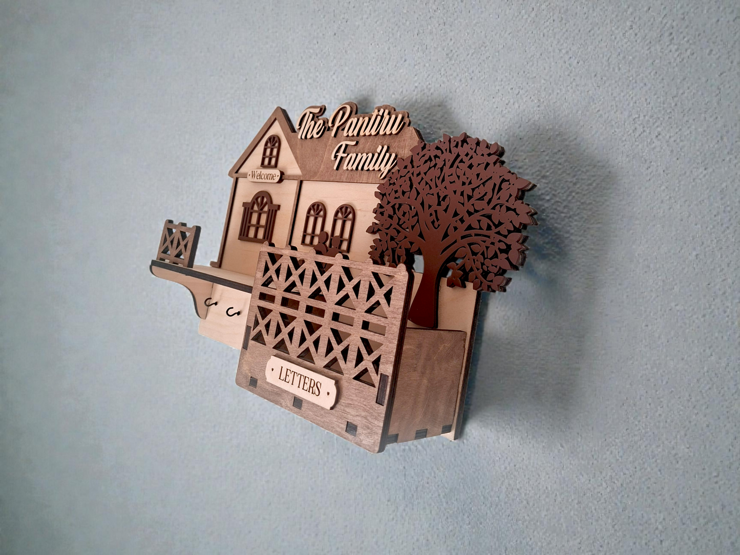 Wooden house-shaped letter holder with 'The Pantry Family' text on a gray background