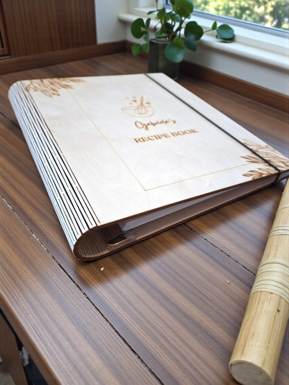 Recipe book on a wooden surface with a plant in the background