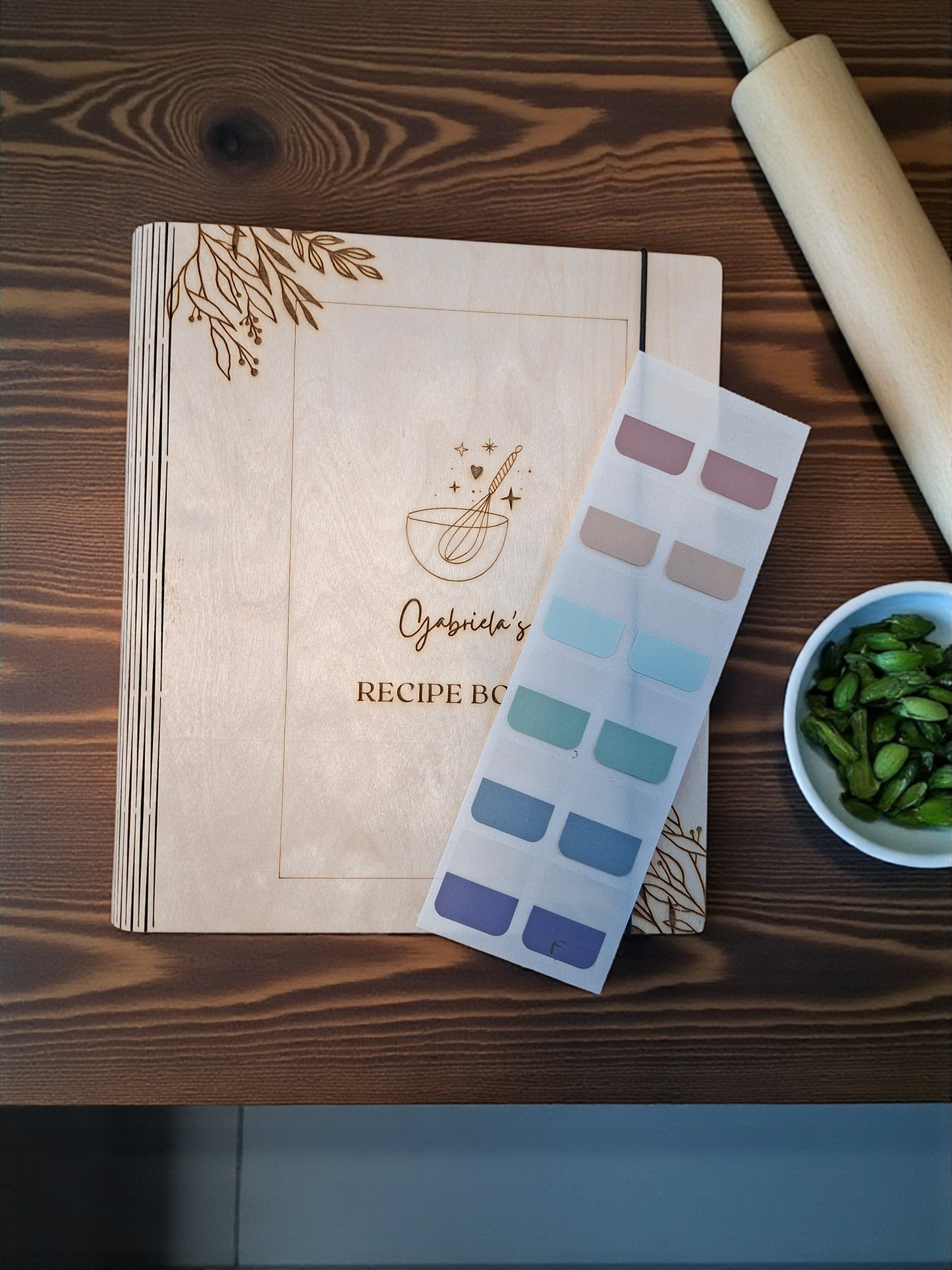 Recipe book with a rolling pin, color swatch, and bowl of green beans on a wooden surface