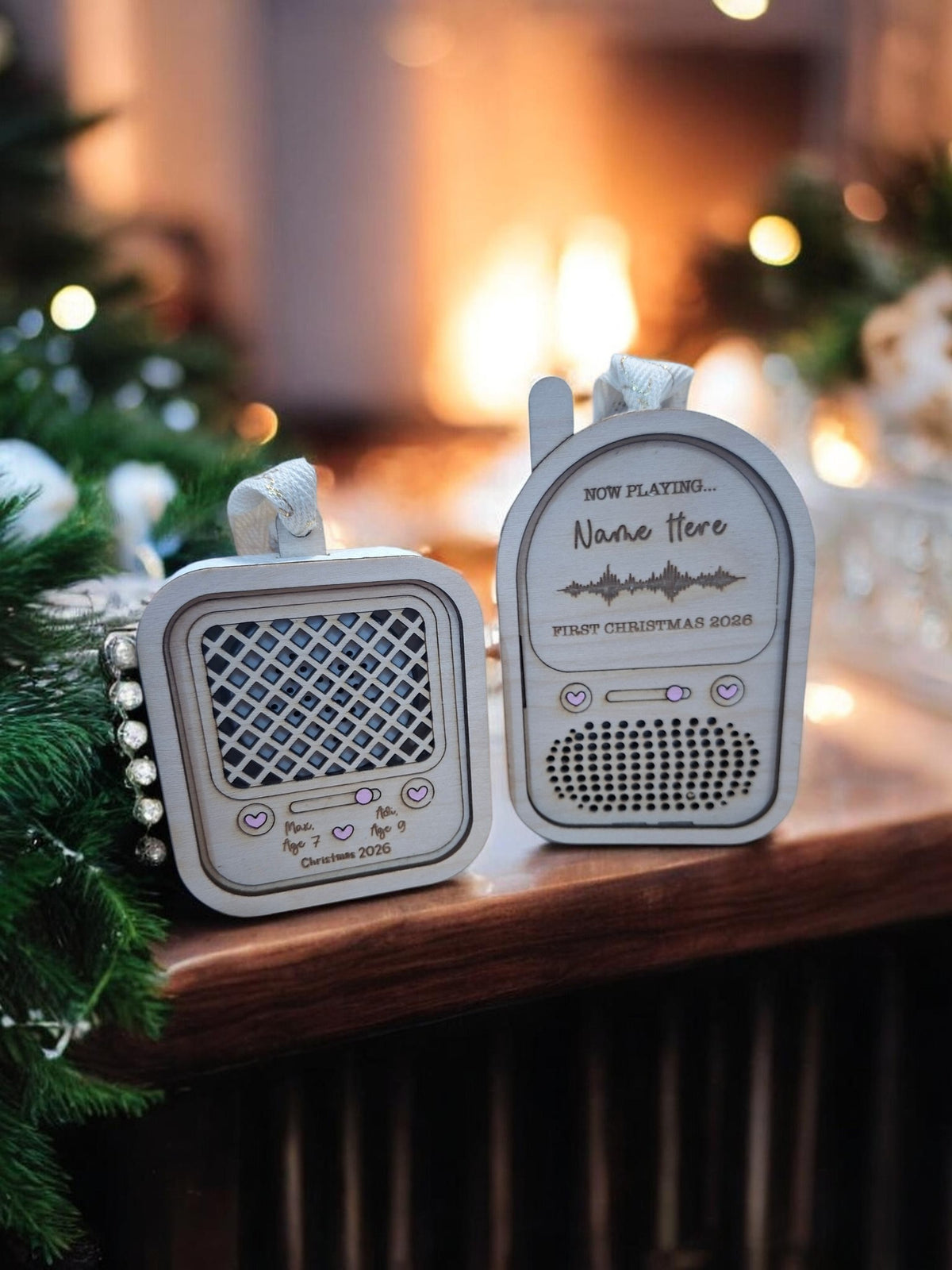 Two personalized Christmas radio ornaments displayed on a wooden mantel with a warm, blurred fireplace and holiday tree lights in the background.