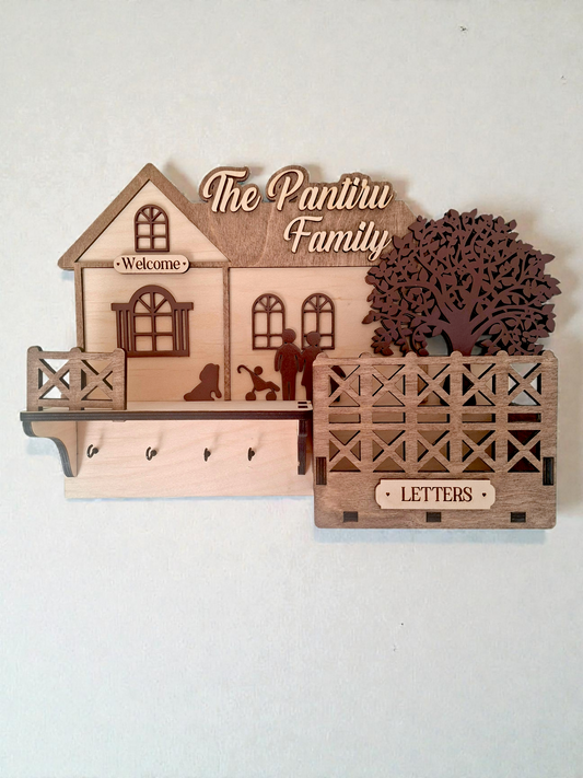 Personalised wooden wall key holder with hooks and a letter box, engraved with 'The Pantiru Family' and decorated with a house and tree motif.