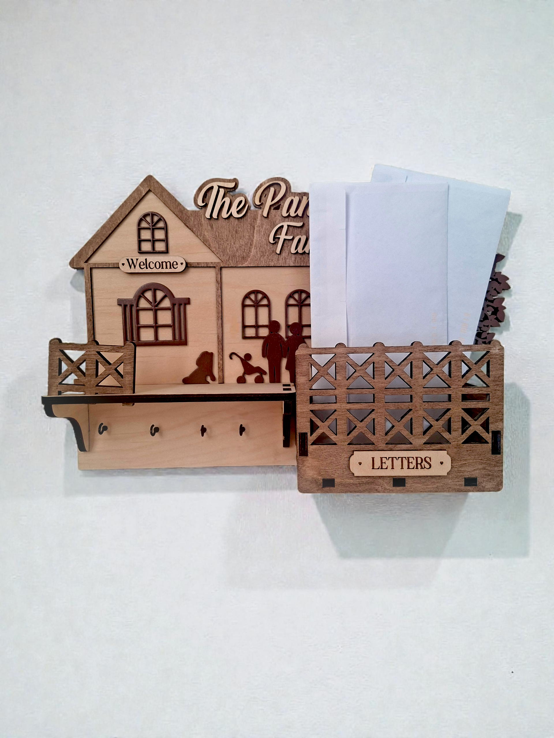 Wooden house-shaped key holder with 'The Paw Family' text and letter holder on a white background
