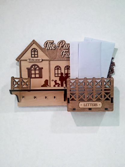 Wooden house-shaped key holder with 'The Paw Family' text and letter holder on a white background